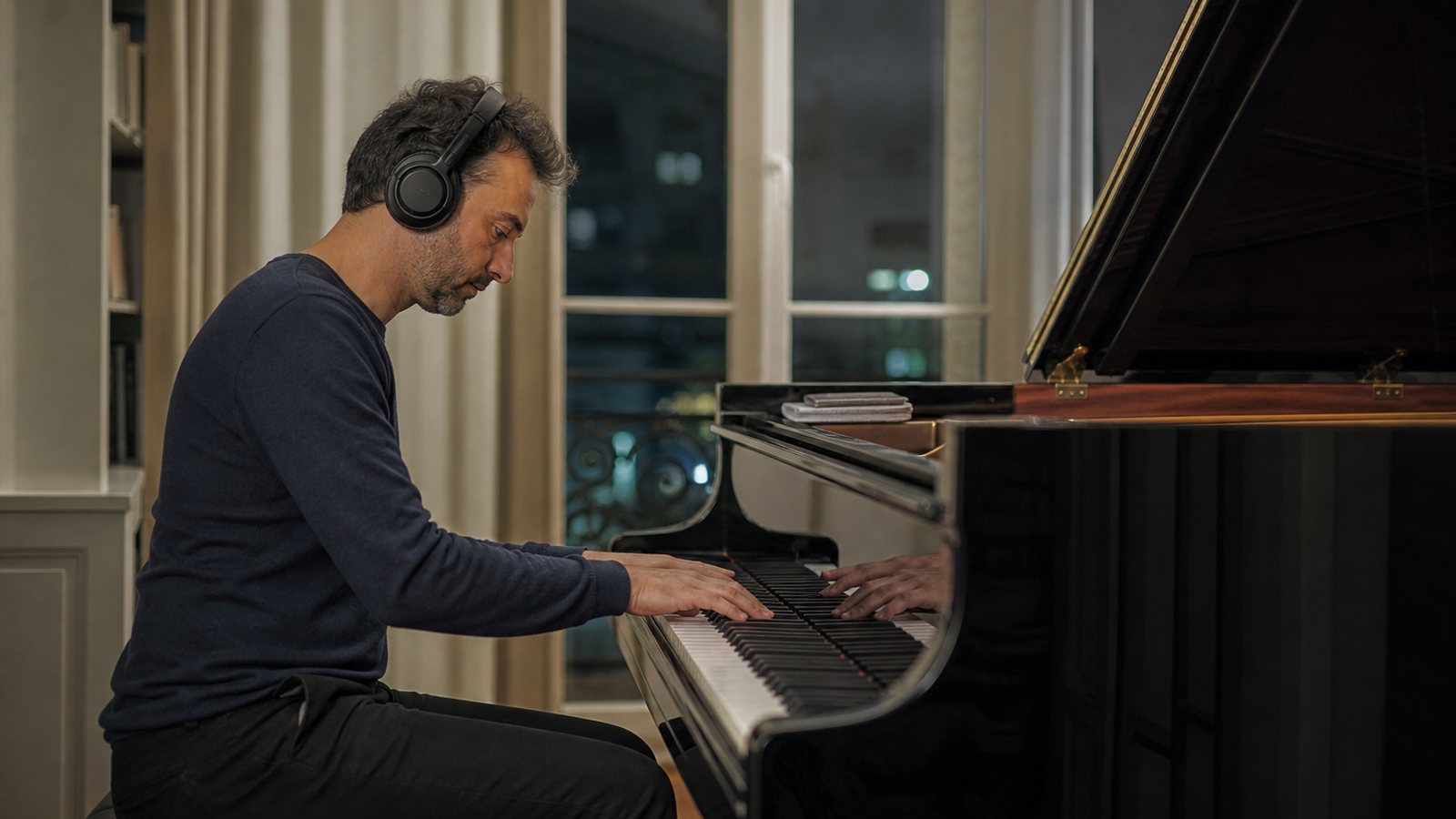 Pianiste au casque devant un piano à queue équipé d'un dispositif silencieux le soir